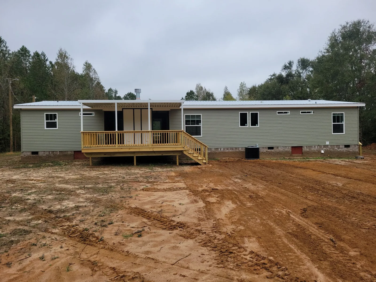 Wood deck with a porch cover, railings, and side stairs along a manufactured home.