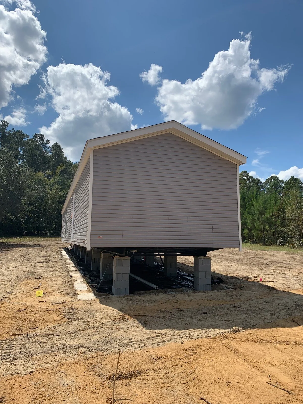 Before skirting installation: a manufactured home with exposed block supports and open space beneath the home.