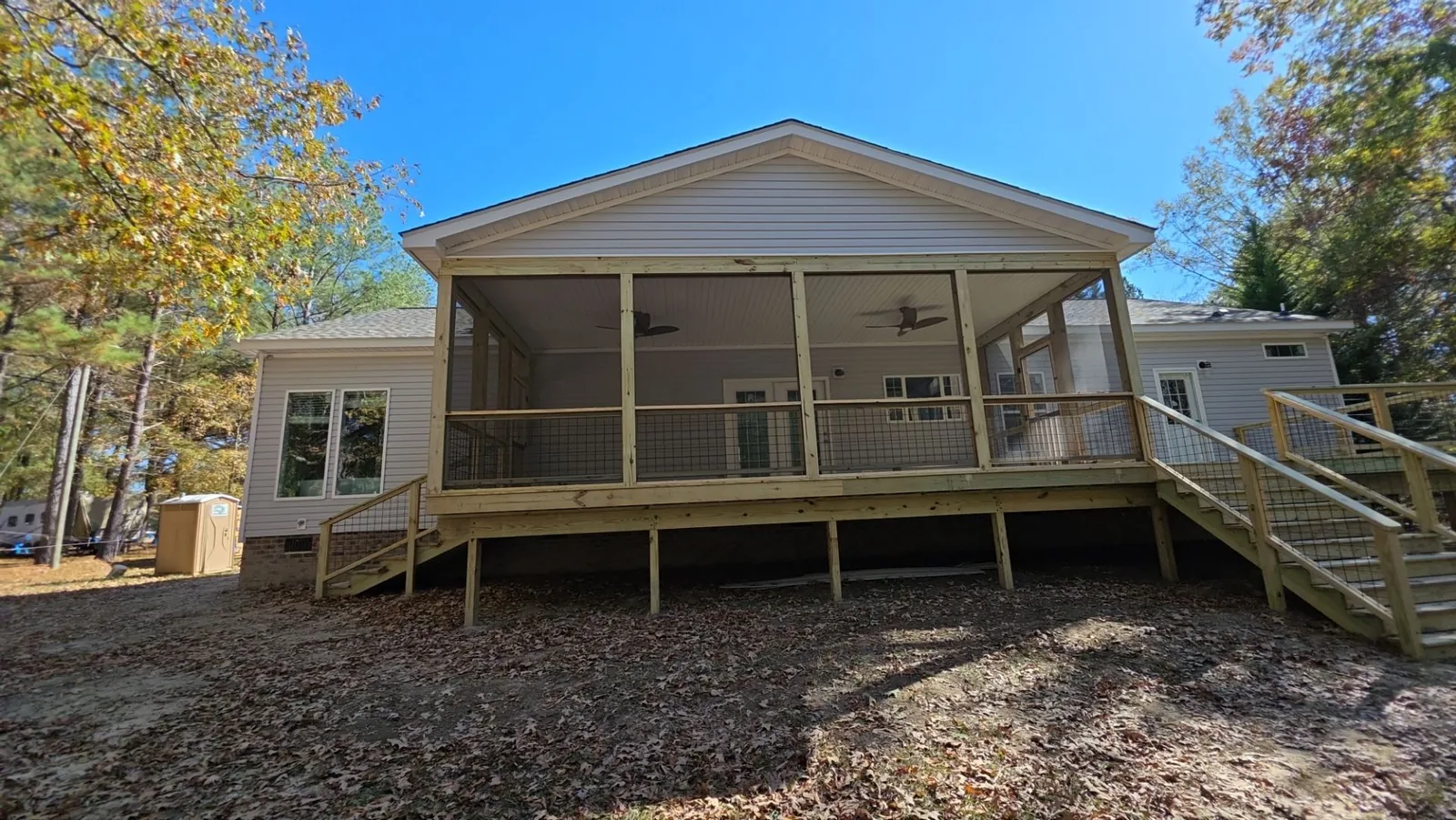 Large screened porch with a gable roof, ceiling fans, wood framing, and steps.