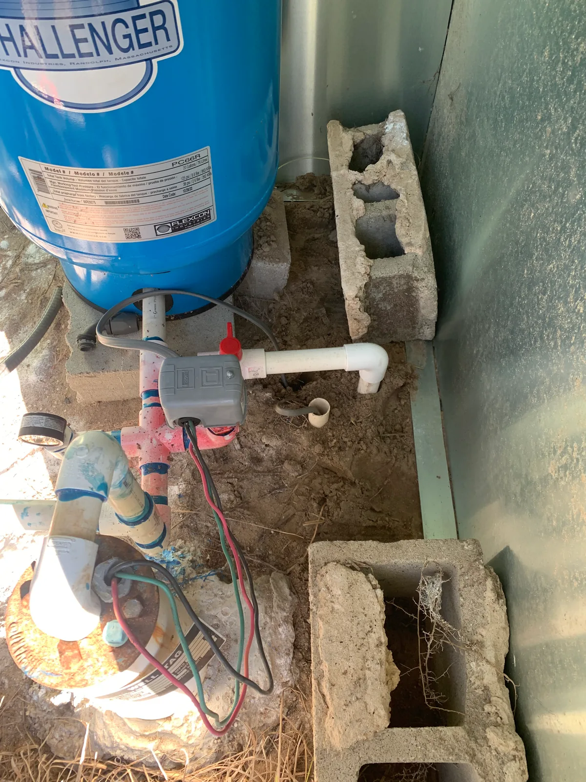 Close view of a well pressure tank, pressure gauge, switch, and piping during service.