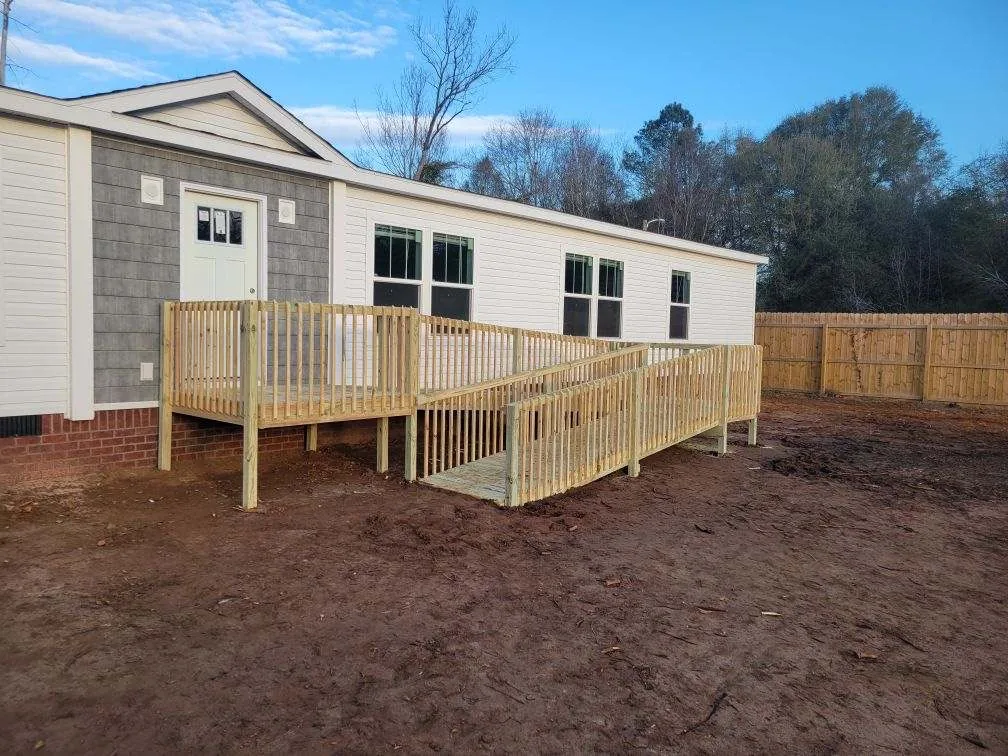 Wood entry deck and access ramp with railings at a manufactured home.