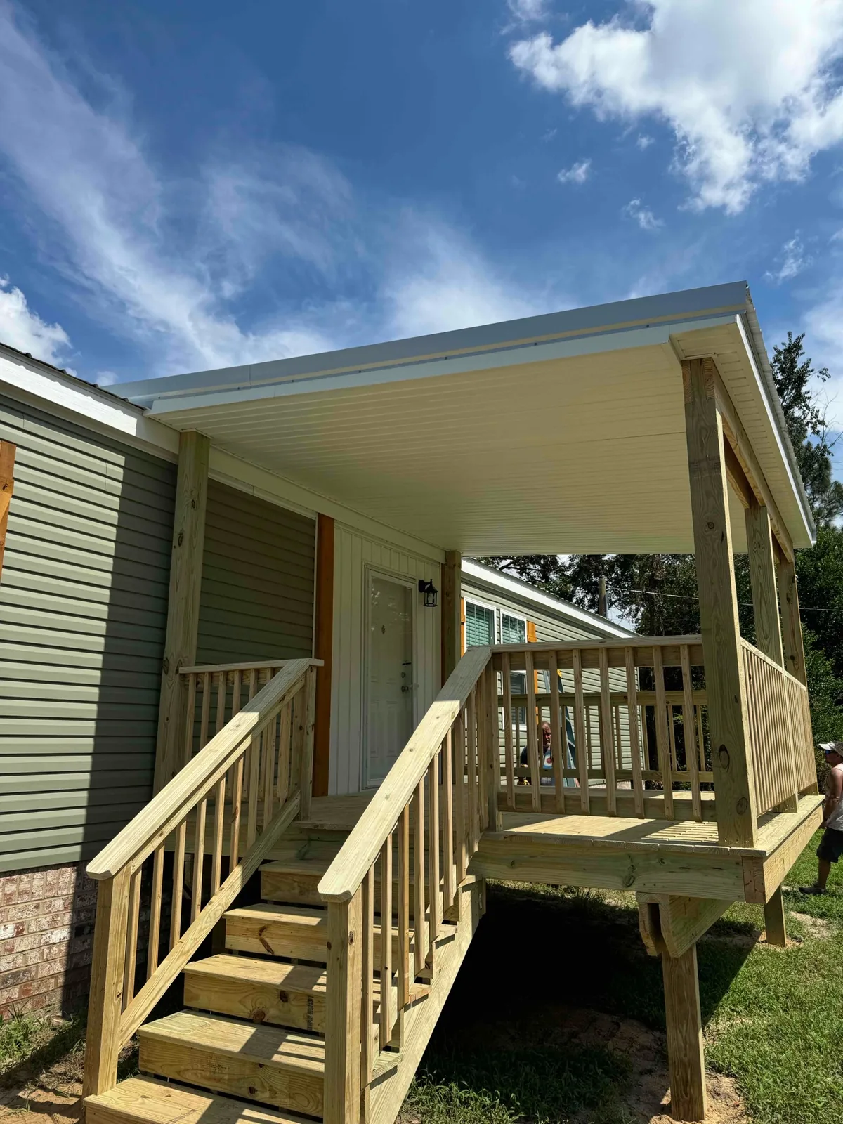 Covered wood entry porch with stairs, railings, and a finished white ceiling.